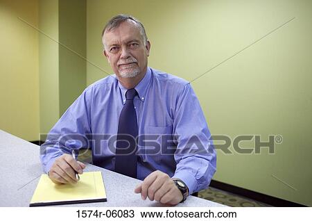 Portrait of a businessman sitting in an office View Large Photo Image Stock Image - Portrait of a businessman sitting in an office. Fotosearch