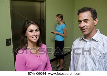Portrait of a businesswoman and a businessman standing in front of an elevator View Large Photo Image Picture - Portrait of a businesswoman and a businessman standing in front of an elevator. Fotosearch