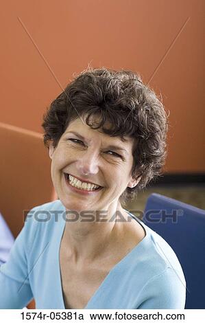 Stock Image - Portrait of a businesswoman smiling in an office. Fotosearch
