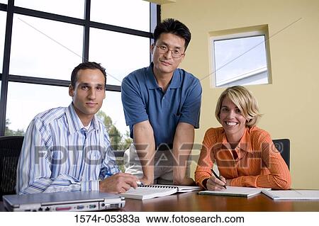 Stock Image - Portrait of two businessmen and a businesswoman in a conference room. Fotosearch