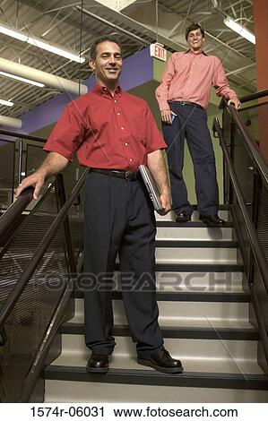 Portrait of two businessmen standing on stairs in an office View Large Photo Image Stock Image - Portrait of two businessmen standing on stairs in an office. Fotosearch