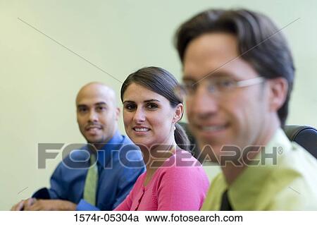 Two businessmen and a businesswoman sitting in a conference room View Large Photo Image Stock Image - Two businessmen and a businesswoman sitting in a conference room. Fotosearch