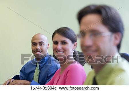 Two businessmen and a businesswoman sitting in a conference room View Large Photo Image Stock Image - Two businessmen and a businesswoman sitting in a conference room. Fotosearch