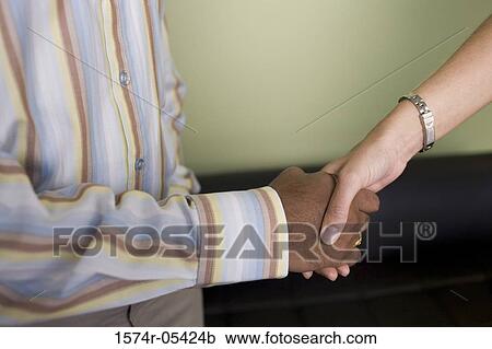 Stock Image - Businessman and a businesswoman shaking hands. Fotosearch