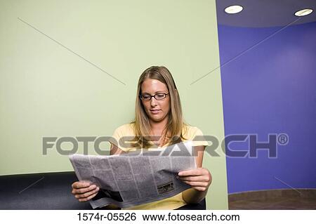 Stock Photograph - Businesswoman sitting on a couch reading a newspaper. Fotosearch