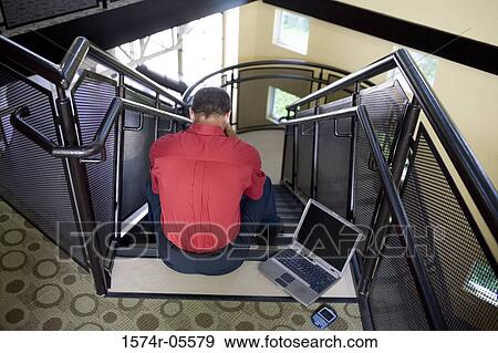 High angle view of a businessman sitting on stairs with a laptop besides him View Large Photo Image Stock Photo - High angle view of a businessman sitting on stairs with a laptop besides him. Fotosearch