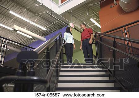 Stock Photo - Low angle view of a businessman and a businesswoman standing on stairs. Fotosearch