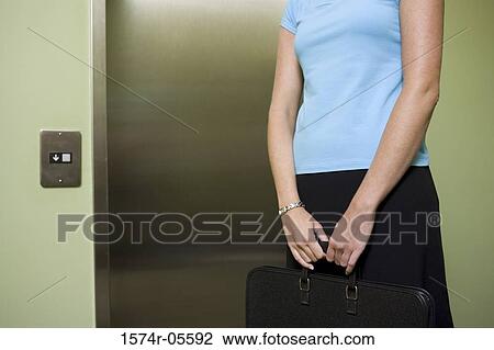 Mid section view of a businesswoman waiting for an elevator View Large Photo Image Stock Image - Mid section view of a businesswoman waiting for an elevator. Fotosearch