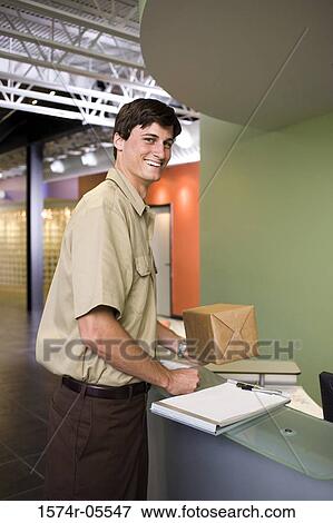 Portrait of a delivery man holding a parcel View Large Photo Image Stock Photo - Portrait of a delivery man holding a parcel. Fotosearch