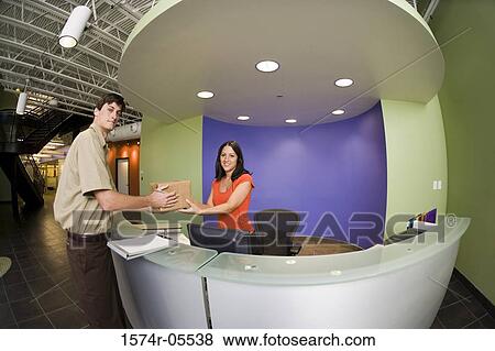 Portrait of a receptionist receiving a package from a delivery man View Large Photo Image Stock Photo - Portrait of a receptionist receiving a package from a delivery man. Fotosearch