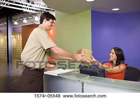 Receptionist receiving a package from a delivery man View Large Photo Image Stock Photo - Receptionist receiving a package from a delivery man. Fotosearch
