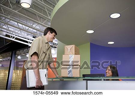 Receptionist receiving a package from a delivery man View Large Photo Image Stock Photo - Receptionist receiving a package from a delivery man. Fotosearch
