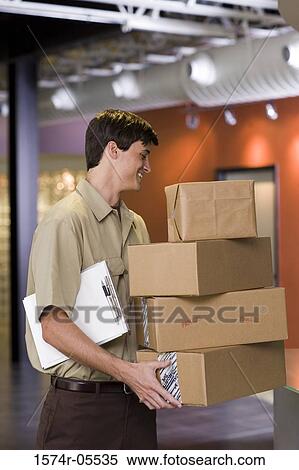 Stock Photography - Side profile of a delivery man holding a stack of boxes. Fotosearch