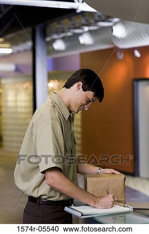 Side profile of a delivery man writing on a clipboard View Large Photo Image Stock Image - Side profile of a delivery man writing on a clipboard. Fotosearch