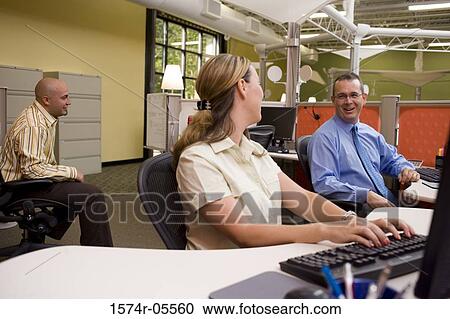 Stock Image - Two businessmen and a businesswoman in an office. Fotosearch