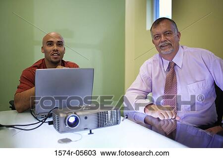 Two businessmen smiling during a slide presentation View Large Photo Image Stock Image - Two businessmen smiling during a slide presentation. Fotosearch