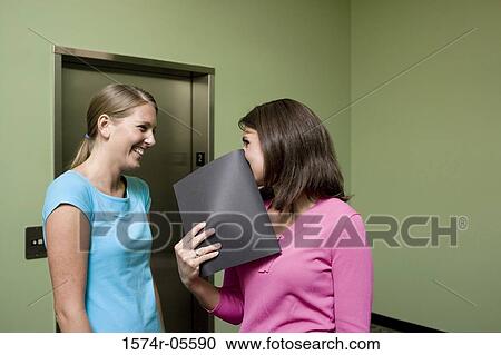 Two businesswomen smiling while waiting for an elevator View Large Photo Image Stock Image - Two businesswomen smiling while waiting for an elevator. Fotosearch