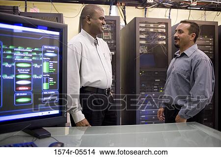Two technicians standing in front of a network server View Large Photo Image Picture - Two technicians standing in front of a network server. Fotosearch