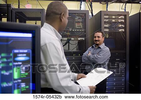 Two technicians talking in front of a network server View Large Photo Image Stock Image - Two technicians talking in front of a network server. Fotosearch