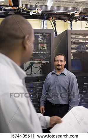 Two technicians talking in front of a network server View Large Photo Image Stock Image - Two technicians talking in front of a network server. Fotosearch