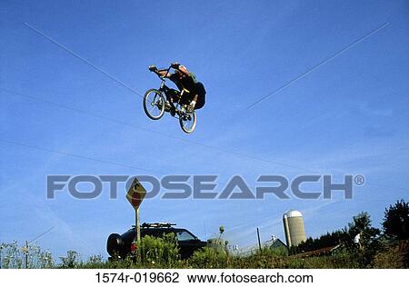 Low angle view of a man performing stunts on a bicycle View Large Photo Image Stock Image - Low angle view of a man performing stunts on a bicycle. Fotosearch