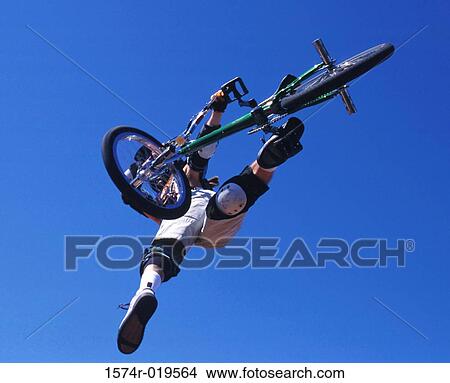 Low angle view of a person performing stunts on a bicycle View Large Photo Image Picture - Low angle view of a person performing stunts on a bicycle. Fotosearch