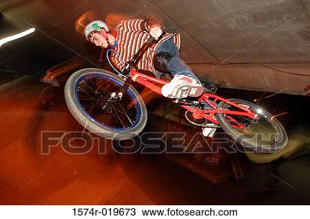 Low angle view of a teenage boy performing stunts on a bicycle View Large Photo Image Stock Image - Low angle view of a teenage boy performing stunts on a bicycle. Fotosearch