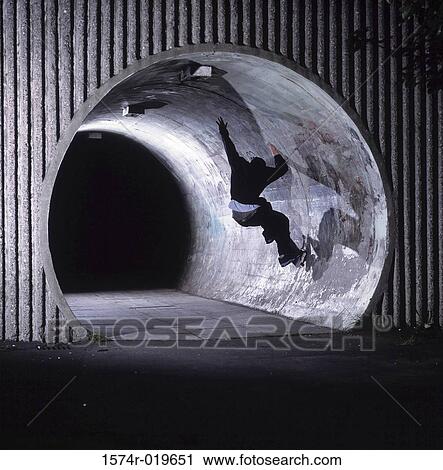 Rear view of a person skateboarding in a tunnel View Large Photo Image Stock Image - Rear view of a person skateboarding in a tunnel. Fotosearch