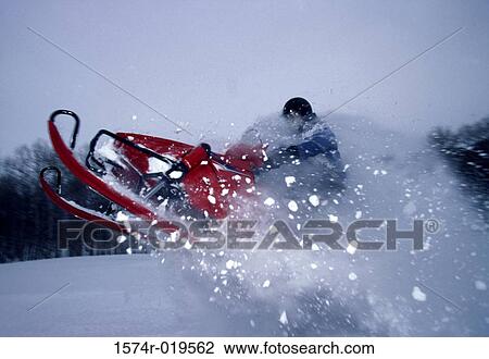 Stock Image - Side profile of a man riding a snowmobile. Fotosearch