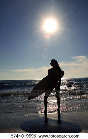 Silhouette of a young woman carrying a surfboard on the beach View Large Photo Image Stock Photography - Silhouette of a young woman carrying a surfboard on the beach. Fotosearch