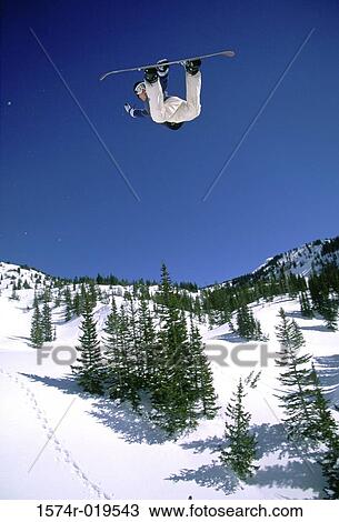 Stock Image - Snowboarder performing stunt in midair. Fotosearch