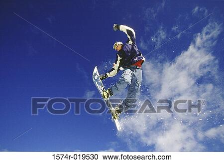 Stock Image - Teenager performing stunt on snowboard. Fotosearch