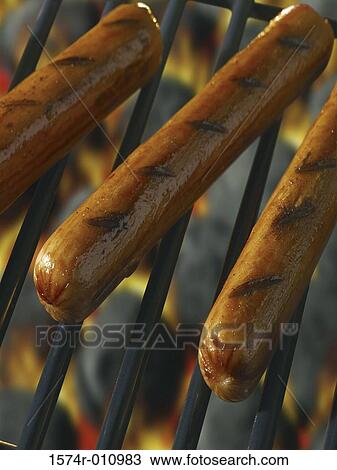 Stock Image - Close-up of hot dogs cooking on a grill. Fotosearch
