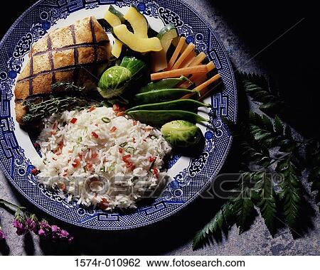 Stock Image - Grilled fish served with rice and vegetables. Fotosearch