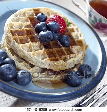 Stock Photograph - High angle view of blueberries and a strawberry on waffles. Fotosearch