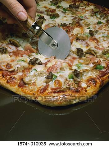 Person's hand cutting pizza with a pizza cutter View Large Photo Image Stock Photography - Person's hand cutting pizza with a pizza cutter. Fotosearch