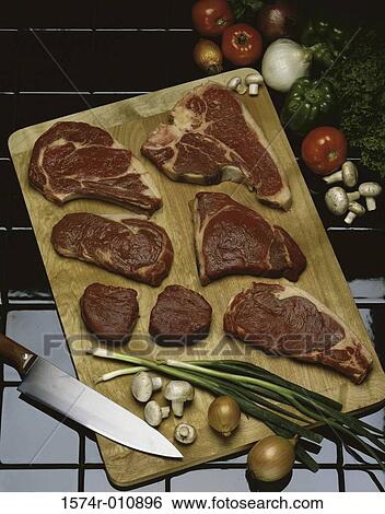 Stock Photograph - Raw beef steaks on a cutting board. Fotosearch