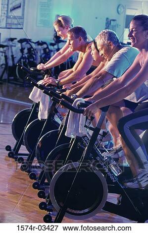 Group of people on exercise bikes in a health club View Large Photo Image Stock Photo - Group of people on exercise bikes in a health club. Fotosearch
