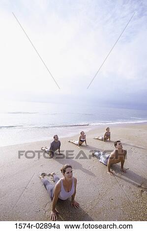 Group of people performing yoga on the beach View Large Photo Image Stock Image - Group of people performing yoga on the beach. Fotosearch