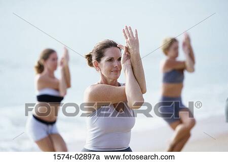 Group of people performing yoga on the beach View Large Photo Image Stock Image - Group of people performing yoga on the beach. Fotosearch