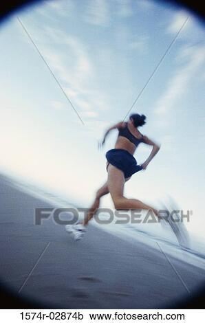 Low angle view of a woman running on the beach View Large Photo Image Stock Image - Low angle view of a woman running on the beach. Fotosearch