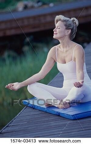 Stock Image - Mid adult woman meditating. Fotosearch