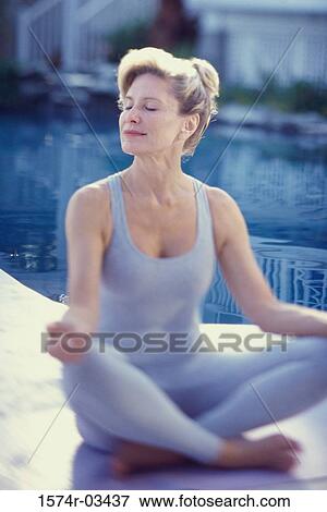 Stock Photo - Mid adult woman meditating. Fotosearch