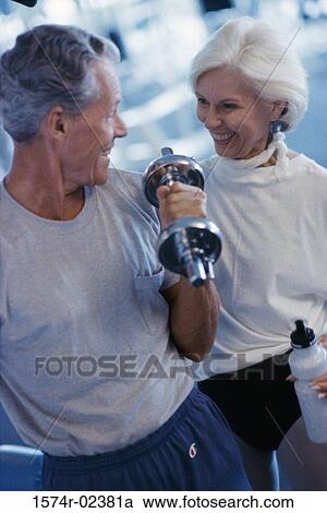 Stock Image - Senior couple exercising in a health club. Fotosearch