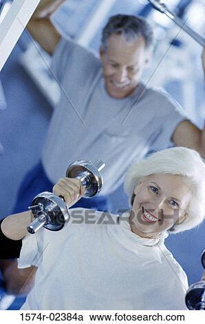 Stock Image - Senior couple exercising in a health club. Fotosearch