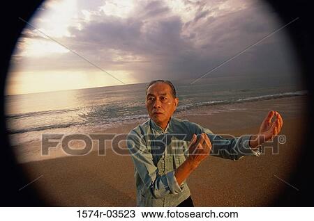 Stock Image - Senior man practicing Tai Chi on the beach. Fotosearch