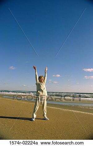 Stock Image - Senior woman exercising on the beach. Fotosearch