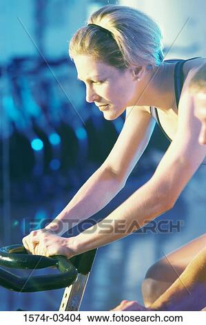 Side profile of a young woman exercising on a cycling machine View Large Photo Image Picture - Side profile of a young woman exercising on a cycling machine. Fotosearch
