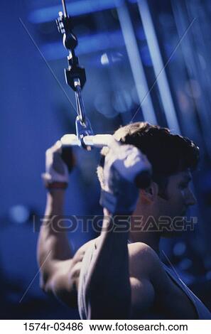 Young man exercising on a lateral pull-down weight machine View Large Photo Image Stock Photograph - Young man exercising on a lateral pull-down weight machine. Fotosearch
