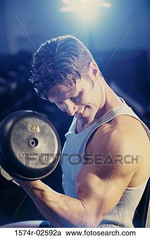 Young man exercising with dumbbells View Large Photo Image Stock Image - Young man exercising with dumbbells. Fotosearch